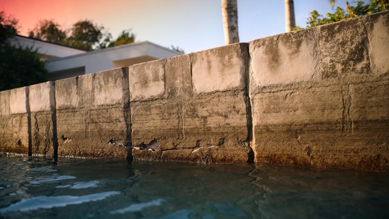 Miami canal seawall meeting deep blue water at golden hour, representative of the waterfront communities we serve